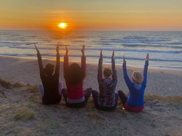 dziewczyny ćwiczące jogę na plaży przy zachodzie słońca
